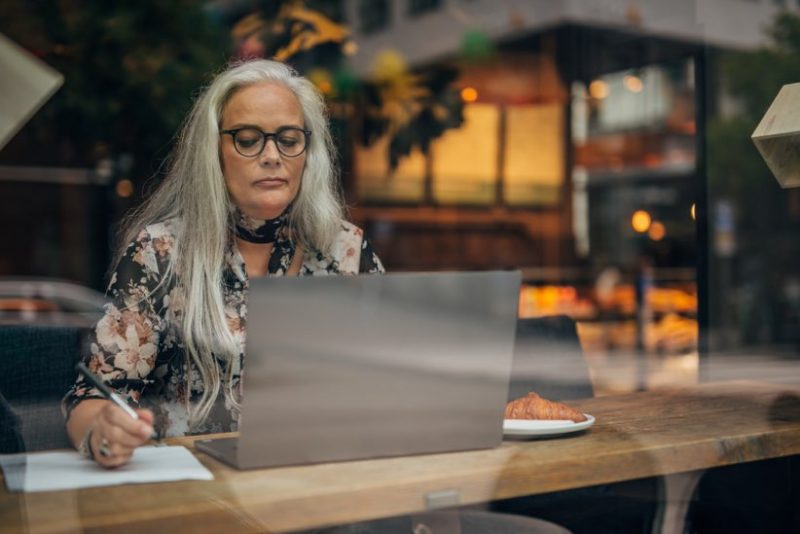 Kvinna som sitter med sin laptop på cafe