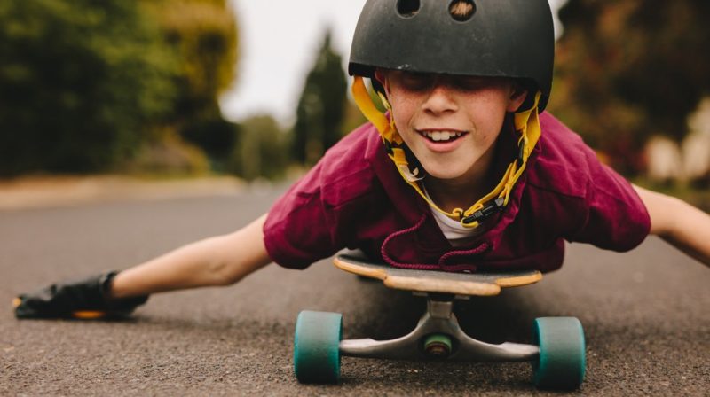 närbild på barn som ligger på mage på skateboard